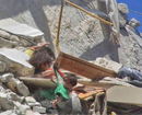 Syrian girl grabs baby sister from shirt in a bombed building’s rubble